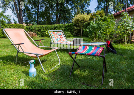 Garden sunbeds on green grass, bamboo fence background. Garden bed