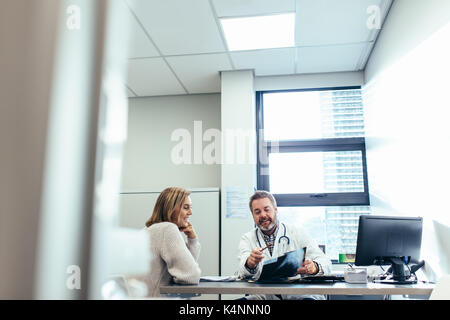 Medicine professional explaining diagnosis of x-ray to patient in clinic. Male physician explaining medical scan result to woman. Stock Photo