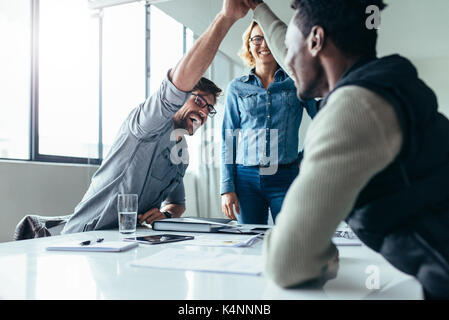 Two colleagues giving high five in meeting. Business people celebrating success in conference room. Stock Photo