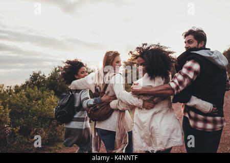 Friends hiking in nature. Group of man and women walking together in countryside. Happy young people turning around and looking at camera. Stock Photo