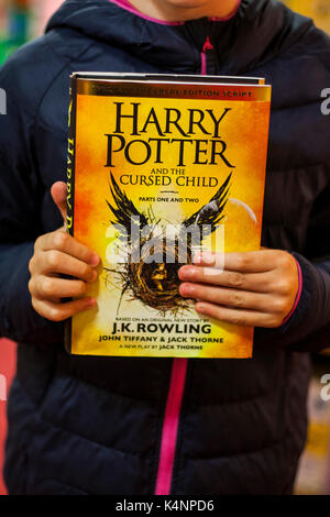 Child holding a J.K. Rowling book, Harry Potter and the cursed child, kids books, childrens books, harry potter books, novels, reading concept Stock Photo