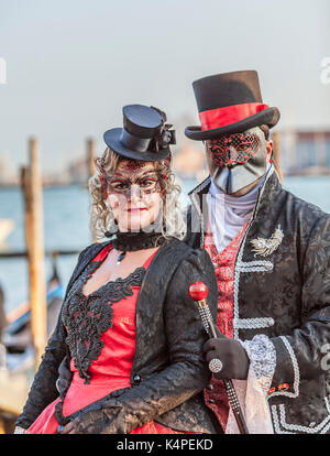Venice, Italy- February 18th, 2012: Environmental portrait of an unidentified couple wearing black disguises and traditional Venetian masks during the Stock Photo