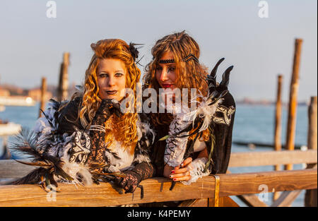 Venice, Italy-February 18,2012: Portrait of two young women wearing a beautiful specific costume near the gondola's dock in San Marco Square in venice Stock Photo
