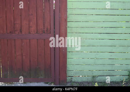 Brown painted wooden fence next to a brick wall Stock Photo