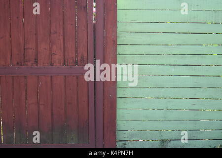 Brown painted wooden fence next to a brick wall Stock Photo