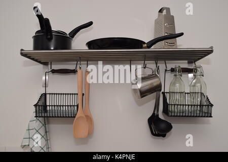 New, clean kitchen utensils hanging on the kitchen wall Stock Photo