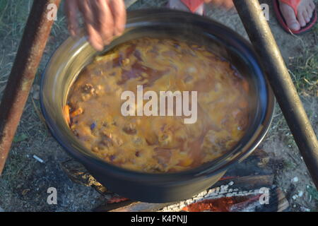 Juicy bubbling stew in a large pot cooking outdoors Stock Photo