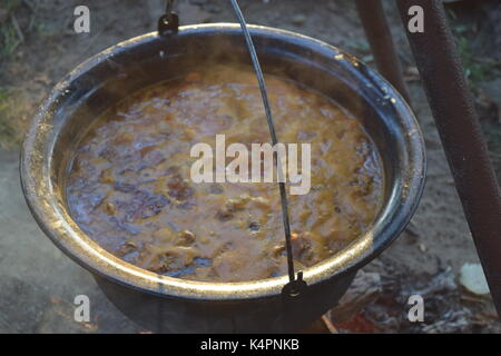 Juicy bubbling stew in a large pot cooking outdoors Stock Photo