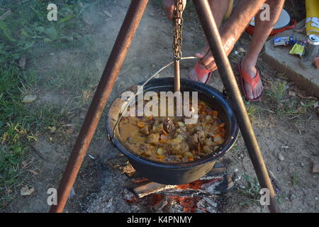 Juicy bubbling stew in a large pot cooking outdoors Stock Photo