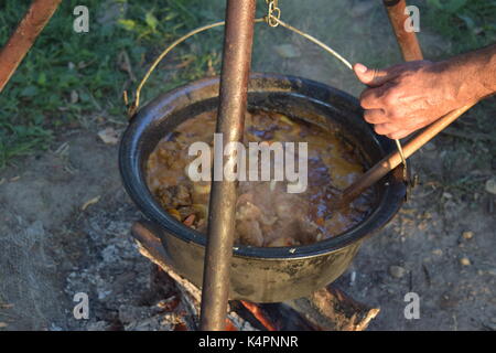 Juicy bubbling stew in a large pot cooking outdoors Stock Photo