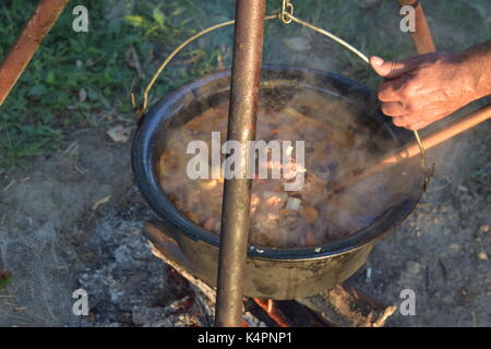 Juicy bubbling stew in a large pot cooking outdoors Stock Photo