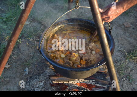 Juicy bubbling stew in a large pot cooking outdoors Stock Photo