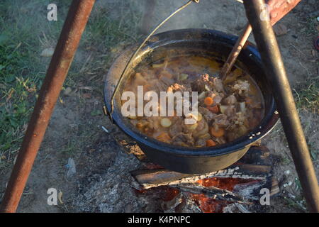 Juicy bubbling stew in a large pot cooking outdoors Stock Photo