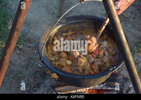 Juicy bubbling stew in a large pot cooking outdoors Stock Photo