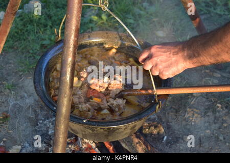 Juicy bubbling stew in a large pot cooking outdoors Stock Photo