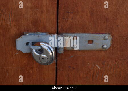 Small metal padlock on a wooden shed Stock Photo