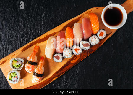 Various kinds of sushi served on a platter with soy sauce, wasabi and pickled ginger. Stock Photo