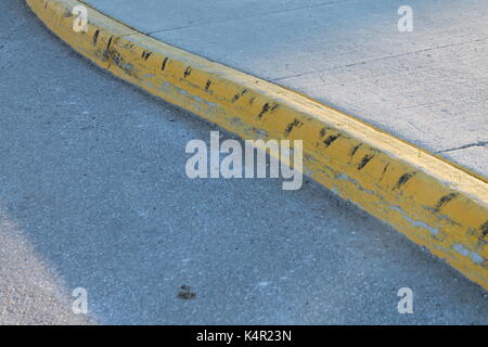 Yellow street curd with school bus black rubber tire marks Stock Photo