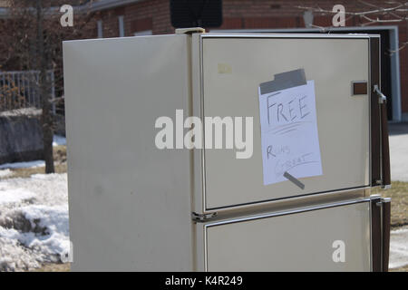 An old refrigerator on the curb of a residential property in Barrie Ontario with a sign that says "Free Runs Great" Stock Photo
