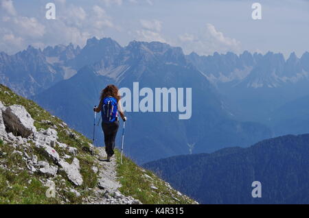 Young femaie trekker hiking on a trail in the Dolomites, Italy, range of Marmarole