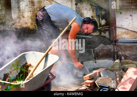 Worker cuts the bricks with a cut-off grinder. Stock Photo