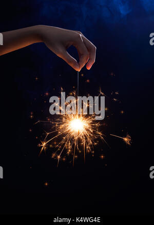 Female Hand holding a sparkler on dark background Stock Photo