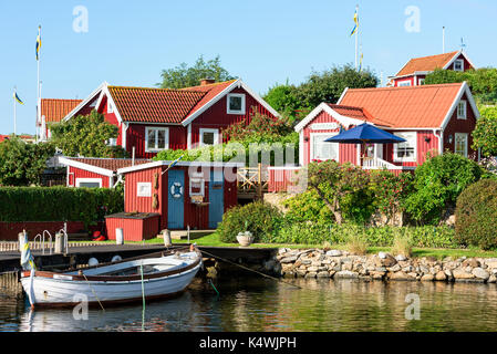 Karlskrona, Sweden - August 28, 2017: Travel documentary of the city surroundings. Red and white traditional coastal vacation cabins and moored boat i Stock Photo