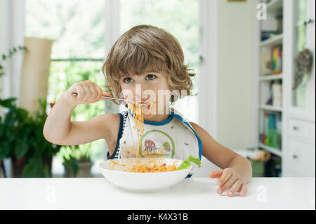 Portrait of a cute young boy making a mess while eating pasta for lunch Stock Photo