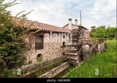 Old water mill with iron water wheel. Stock Photo