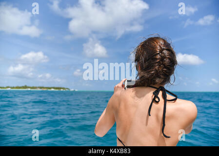 Tourist Woman taking sea photo with her smart phone at Maldives Stock Photo
