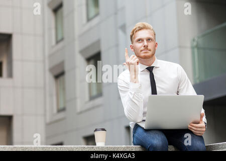 I have idea! Handsome ginger businessman with beard looking up and finger up. Outdoor shot Stock Photo