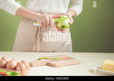 House wife wearing apron making. Steps of making cooking apple cake. Cutting green apple. Stock Photo