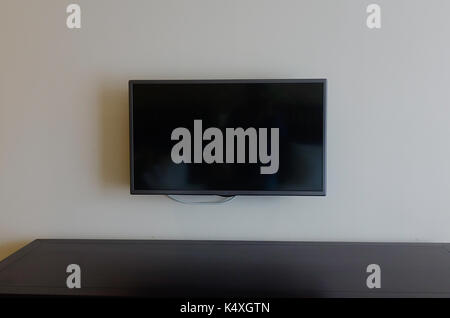 Black LCD or LED tv screen hanging on a wall in bed room of hotel Stock Photo