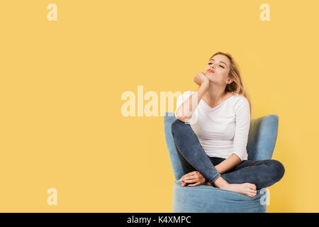 Young blonde woman on chair is bored. Picture includes copy space Stock Photo
