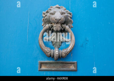 Old lion shape door knocker on an old blue door. Stock Photo
