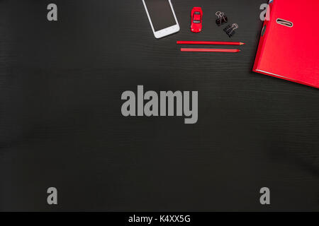 Black red white office desk business background Smart phone on black wooden desktop in modern office with accessories. Stock Photo