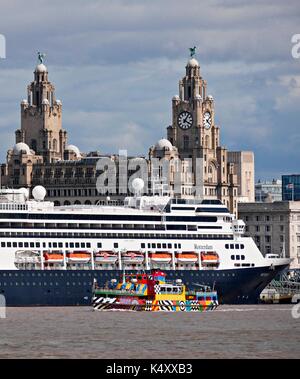 Mersey Ferry in dazzle livery sails past cruise liner and Royal Liver Building at the Pier Head, Liverpool. Stock Photo