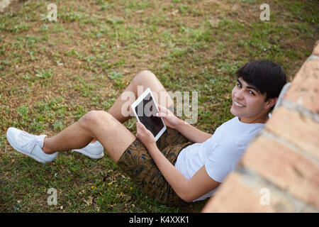 Aerial portrait of happy man relaxing outside with tablet Stock Photo