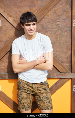 Portrait of young happy man standing with folded arms Stock Photo