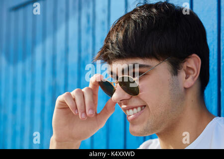 Side portrait of young happy man holding sunglasses smiling Stock Photo