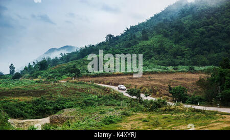 Lonely car driving on the empty road in the mountain and cloud Stock Photo