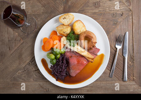 Roast beef dinner with gravy on a plate on a wooden table Stock Photo