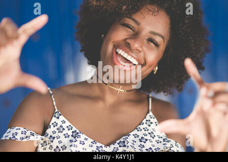 Portrait of pretty afro american woman making frame from hands laughing Stock Photo