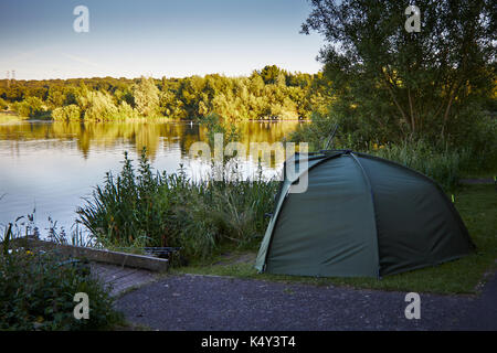 Fishing tent with a fishing rod on the shore of lake. Stock Photo