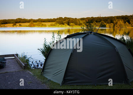 Fishing tent with a fishing rod on the shore of lake. Stock Photo