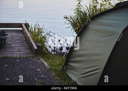 Fishing tent with a fishing rod on the shore of lake. Stock Photo