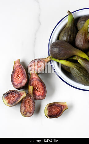 Ficus carica. Fig 'Brown Turkey' in an enamel dish on a marble surface. Stock Photo