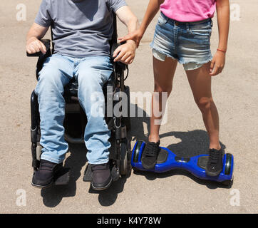 Disabled father playing with daughter on hoverboard. Stock Photo