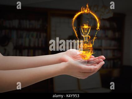 Digital composite of hands with light  fire icon over in the living room. Stock Photo