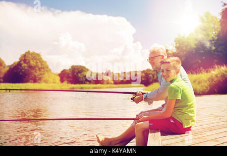 grandfather and grandson fishing on river berth Stock Photo